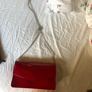 Väska  - En super snygg röd väska som passar perfekt för utgång. Har knutit kedjan för att få den till en axelväska men den går att knyta upp utan problem. Lappen sitter fortfarande kvar. Köpt från zalando med märket even & odd.