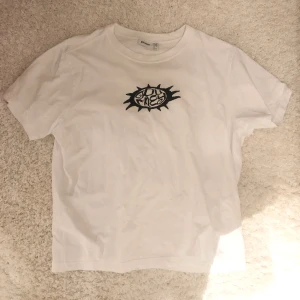 T-shirt med tryck  - Vit T-shirt med svart tryck. Köpt på Weekday i Stockholm. Använd någon enstaka gång, så väldigt bra skick! Snygg oversized passform 
