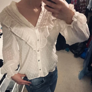 Zara vit blus - En super söt vit zara blus med massa fina volanger och glansiga knappa. Bara använd en gång. Kontakta för flera bilder.