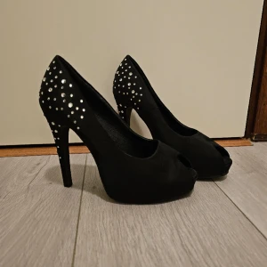 Strassbeklädda pumps  - Beskrivning: Svarta strassbeklädda pumps med peeptoe Märke: Bianco  Storlek: 38 Skick: Använda vid ett tillfälle, mycket gott skick Material:  Nakenkatt finns i hemmet