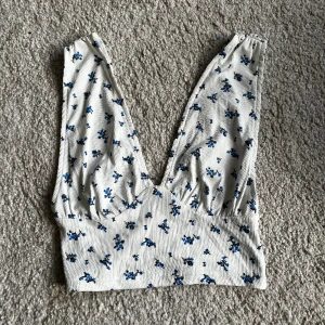 Sommartopp - Vit/blommig V-ringad sommartopp. Nästan aldrig använd då den inte riktigt passade mig och min stil. Finns ett litet hål som knappt syns. Från Cider. Storlek 34 (XS). Tveka inte att höra av dig om du har några frågor eller vill ha fler bilder.