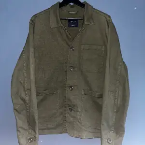 En bekväm grön Overshirt från Jack and Jones med 3 fickor. Storlek L men liten för sin storlek men känns som M ! Stretchigt material med bra utrymme i! Krävs nog en hoodie under för de varma! Nypris: 700kr, säljs inte längre och är knappt använd! 