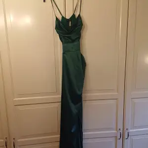 En fin, smaragd-grön klänning med slits. Perfekt till balen eller annat tillfälle!😊 Öppenrygg och öppna sidor med spaghetti band. I bra skick och bara använd en gång!