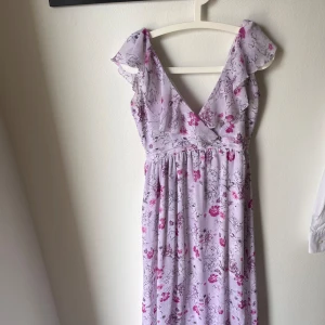 Somrig klänning  - Somrig klänning i nyskick. V-ringad upptill med volang. Djup v-ringad rygg.