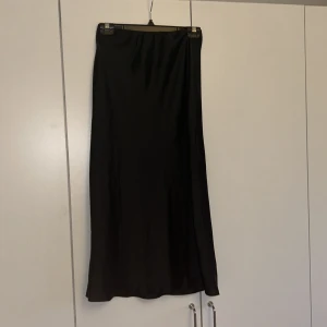 Svart långkjol i satin - Säljer denna svarta satinkjolen från Asos Design. Den är helt oanvänd då den inte passar mig 🫶🏼 Den är i strl 36 och slutar typ vid vaderna på mig som är 166. 