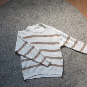Randig tröja - Den här tröjan från lager 157 är vit med ljus bruna ränder. Den är i fint sick men har en liten fläk men den syns nästan inte.