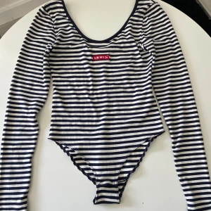 Body från Levis - Oanvänd body med lappar kvar från Levis. Långa ärmar och djup urringning i ryggen, knäppning i grenen. Stl S.