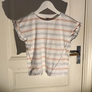 Vitrandig T-shirt - En fin vit T-shirt med ljusrosa och ljusblå ränder. Med ett bra skick 💗9-10 år