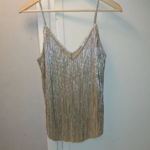 Guldsilvrig nyårstopp Strl S/M - Skitsnyggt linne som skimrar i guld och silver. Strl M/S. Perfekt för nyår :) OBS. Den är avklippt nertill se bild. 