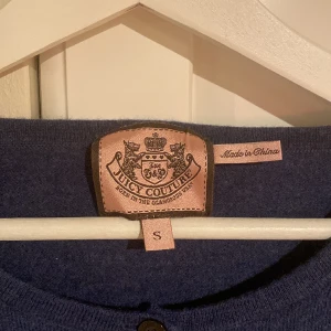 Juicy couture kofta  - Säljer denna juicy couture koftan med rosetter på armarna och vid axlarna! Strl S men är liten i storleken så passar xxs och xs. Materialet är 100% merinoull