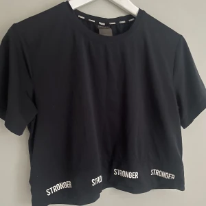 Träningstopp - En svart lite croppad t-shirt perfekt till träning. Superfin och i bra skick, har inte använt så mycket. Från stronger och storlek S. Använd gärna köp nu🫶
