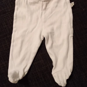 Vita byxor strl. 56 - Vita byxor med inbyggda fötter. I fint begagnat skick, inga hål eller fläckar. Unisex  Tvättad i parfymfritt tvättmedel och utan sköljmedel.