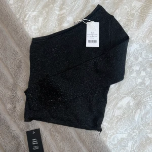 Enarmad Glittrig tröja - Enarmad glittrig tröja från NAKD, säljs pga den inte kommer till användning. Helt ny med lappar på. St XS!  Pris kan diskuteras vid snabb affär 💗