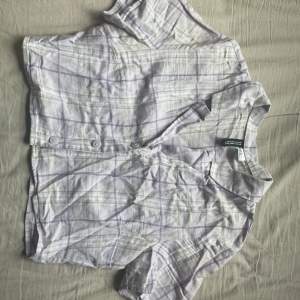 En ljuslila, kort och rutig skjorta från HM, med ljusgröna ränder. 100% bomull, orginalpris 99kr.