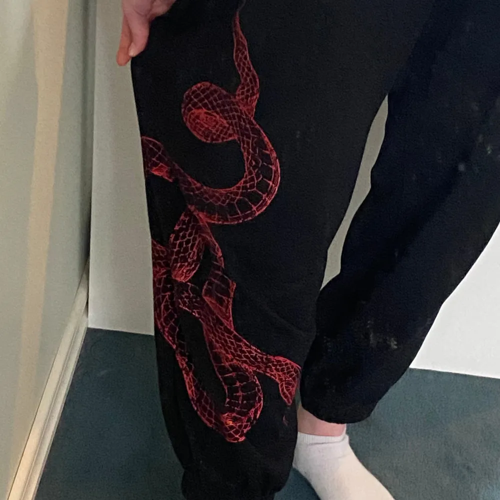 Svarta mjukisbyxor med röd orm på🤍. Jeans & Byxor.