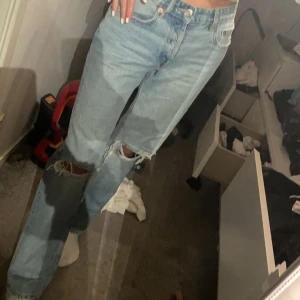 Zara Jeans mid rise - Mid rise jeans från Zara i storlek 36💓 Byxorna är i använt skick och på bilderna kan man se att hålen på knäna har blivit slitna.