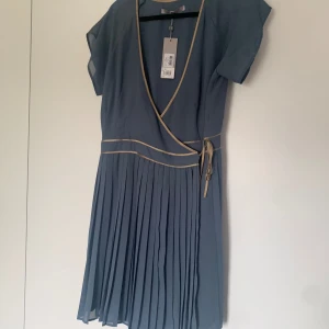 Klänning J Lindeberg - Oanvänd klänning J Lindeberg. Nypris 1199kr.  Stl XL Stor upptill och smal i midjan men kan man sy så går säkert bandet att flytta