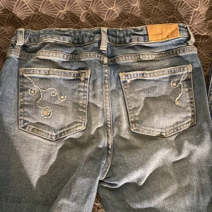 Bootcut lowaist jeans - Blåa bootcut jeans som är lowaisted med broderade detaljer på fickor, från Gina Tricot i storlek 158