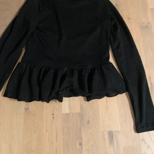 Glittrig blus - Svart glittrig blus med vågor 