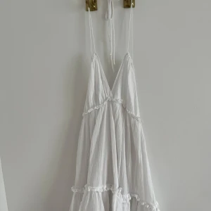 Vit sommarklänning  - Fin klänning som har halterneck och är backless. Använt enbart en gång. Är lite fläckig mot 2 kanter men det är verkligen inget som märks alls som man även kan se på bilderna. 