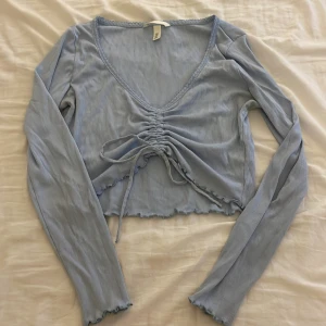 Tröja  - En tunn tröja, med snörning längt fram som bestämmer hur långt upp du vill ha den.