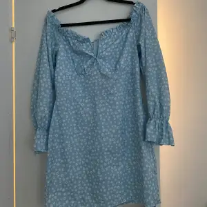 En fin off shoulder-klänning i en fin ljusblå färg med vita blommor på. Köpt från Nelly för 2 år sen, använt 3 gånger.  Frakt: 29kr