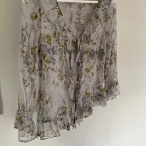 Somrig blus med volanger - Fin blus med volanger och vackra trekvartsärmar. Knyts på två ställen fram, kan öppnas helt som en kofta. Sparsamt använd, fint skick utan defekter 🌸