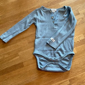 Långärmad body stl 80 - Långärmad body: Newbie Kappahl Blå med söta knappar.  Stl 80 Finns att hämta i Borgholm 