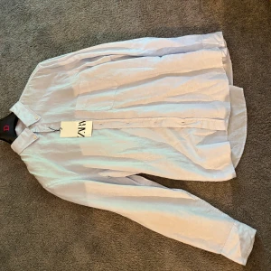 Ljusblå skjorta  - Ljusblå skjorta i tunn bomull. Riktigt fräsch till sommaren. Tyvärr för stor för mig. Storlek L. Nypris runt 500. Bara testad aldrig använd tagen är kvar på.