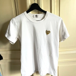 Play Comme des garcons  - En vit T-shirt ifrån Play Comme des garcons med ett guld hjärta. Har denna i storlek L då jag inte ville ha den som en tajt t shirt.  Är själv i storlek S/M.