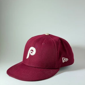 New Era 59Fifty Philadelphia Phillies Mörk Röd Keps Ny - New Era fitted keps i 59Fifty modellen med laget Philadelphia Phillies på, helt ny men har bort plockade stickers. Storlek: 7 3/4” eller 61.5 cm