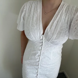 Vit klänning - (till studenten eller andra tillfällen)  - Vit Studentklänning från NA-KD, Storlek 38 - Helt Ny! Klänningen har en elegant design med  knappar längs framsidan och en smickrande passform som markerar midjan. Helt ny och oanvänd. Perfekt för studenten eller andra tillfällen.