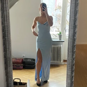 Blå satin klänning/balklänning - Jag säljer min blåa balklänning med slits som är använd 1 gång endast, den är i nytt skick i storlek 36 och kostade nypris 899kr. Jag är 1,70cm och klänningen går ner till marken med klackar!