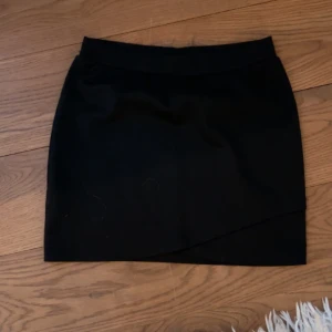 Svart minikjol - Super snygg svart minikjol med en liten dubbelbokning framtill🩷