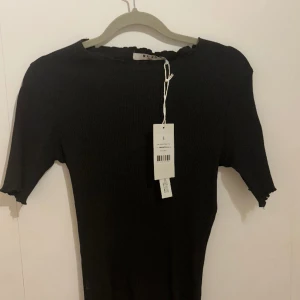 T-shirt från NAKD med volang🤍 - Superfin helt ny ribbad t-shirt från NAKD med volanger!!🥰 Superfin till sommaren och helt ny med lapp kvar, säljer pga. för liten för mig och att returrätten utgått✨