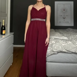 Bal/festklänning - Vinröd lång klänning. Den är uppsydd nertill men inget man ser eller lägger märke till. Har även inbyggda vaddar.