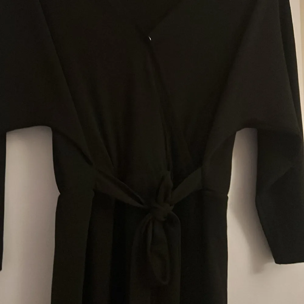 Gullig svart klänning med band i midjan och en viten ”osynlig” knapp vid skärningen . Klänningar.