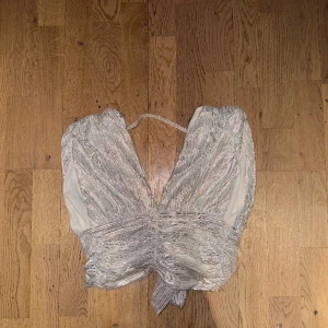 Partytopp  - Silvrig partytopp som man knyter i ryggen från gina tricot! Knappt använd!