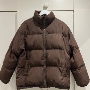 Brun puffer jacka - Använd i bra skick  Nypris 999kr Skick 5/10 En fläck på armen som inte går bort i tvätten därav priset 