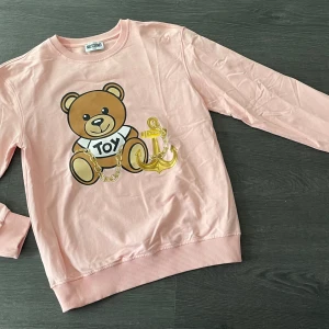 Moschino sweater - Ljusrosa, aldrig använd! Storlek 164, skulle säga xxs/xs typ. Trycket är helt, inga sprickor. 