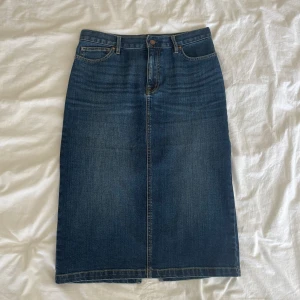 Medellång Jeanskjol - Superfin, medellång jeanskjol i vintage-stil. Kjolen har en slits bak och går att bära både låg och högmidjat!💙 Den är i superfint skick och märket är Muji. Kjolen är i storlek S.