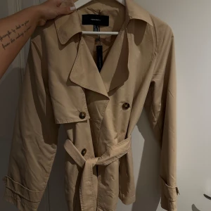 Kort trenchcoat - Trenchcoat från Vero Moda. Helt ny med prislapp. Storlek M