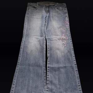 Low waist bootcut jeans med broderade blommor på sidan av benet! Super fina men inte min stil längre 💓Längd 108 cm ytterben, midja 47 cm  rakt över och benöppning 27 cm (längst ner på byxan) 💓