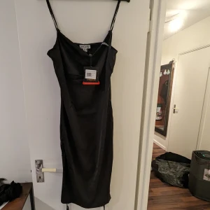 Helt ny klänning - Ny klänning! Svart satin med justerbar längd. Waterfall hals. 