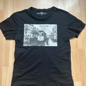 Avenyn t-shirt  - Ett egendesignat tryck på en fräsch secondhandtröja. Ett tryck från vår kollektion ”Noire et Blanche”. Vårt motiv ’Avenyn’ är en svartvit målning inspererad av ett foto från 2019. Som Göteborgare är vi stolta över att kunna inkludera detta motiv!