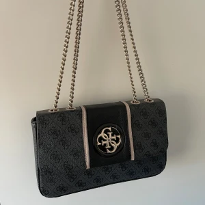Guess väska  - Guess väska i gott med använt skick, flera mindre defekter finns utöver kedjan på bild 4! Hör av dig för bilder på dessa 💓