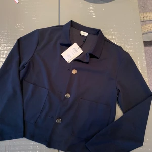 Kavaj marinblå oanvänd - JDY oanvänd marinblå kavajjacka med guldknappar o stora fickor fram. Srl S