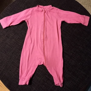 Rosa pyjamas strl 62/68 - Rosa pyjamas i storlek 62/68 från Kappahl. I fint begagnat skick, har några små fläckar på ena benet, syns mer på bilderna än i verkligheten.  Tvättad i parfymfritt tvättmedel och utan sköljmedel.
