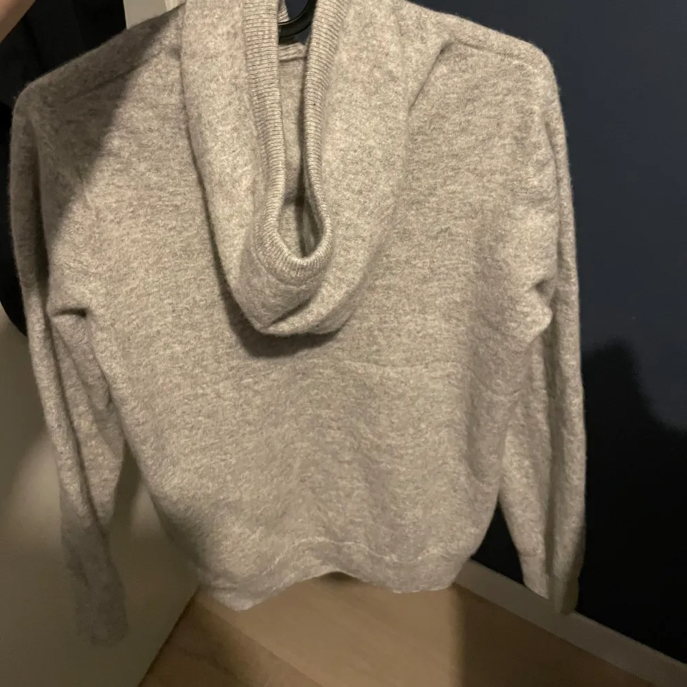 En grå riktigt snygg och skön hoodie som är 100% merinoull. Det finns ingen lapp i tröjan men den är köpt för 1299. Använd några få gånger. . Stickat.