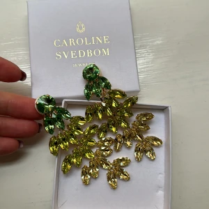 Strass Örhängen Caroline Svedbom clips - Storlek: 90 x 43 mm Plätering: 18K Guld / Rodium Världens högsta kvalité på kristaller Graverad logotyp Designad i Sverige, handgjord i Grekland  Nya o oanvända. 